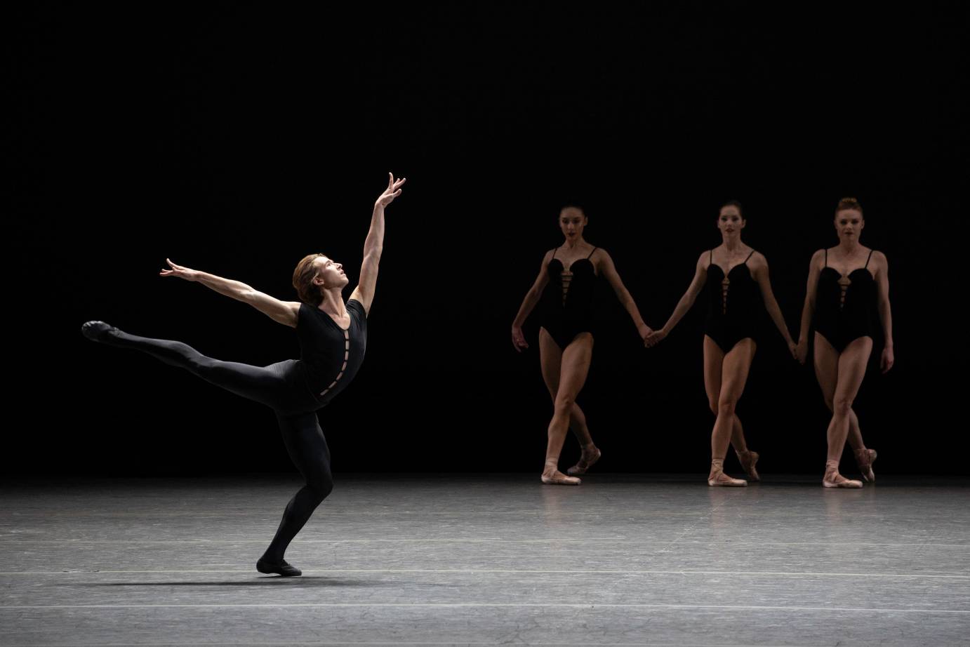 A man in amplified arabesque is in front of three women